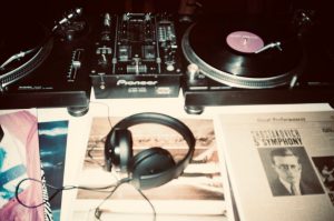 Close-up of a vintage DJ setup featuring turntables, vinyl records, and headphones, capturing the essence of retro music.